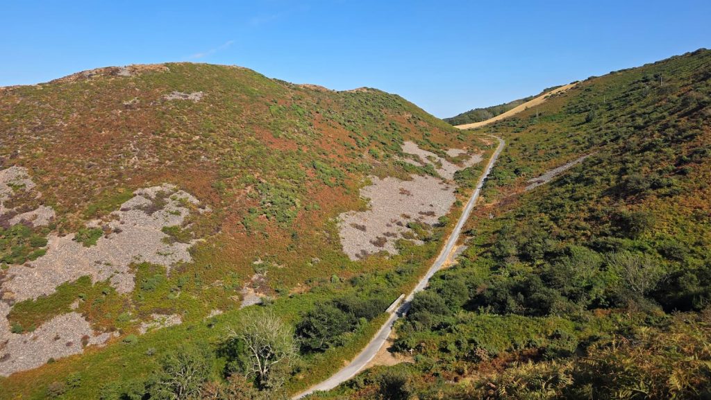 Countisbury Hill on a bright, sunny, clear day surrounded by moorland and a steep road leading down the hill.