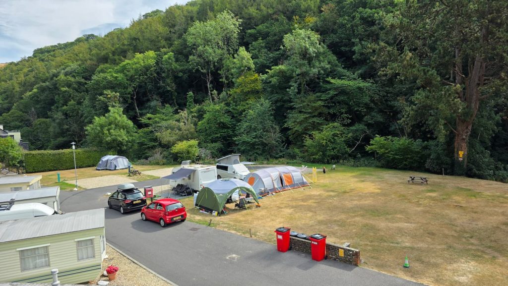 View over Sunny Lyn Campsite in Lynton Devon, with caravans, tents and vehicles surrounded by trees.
